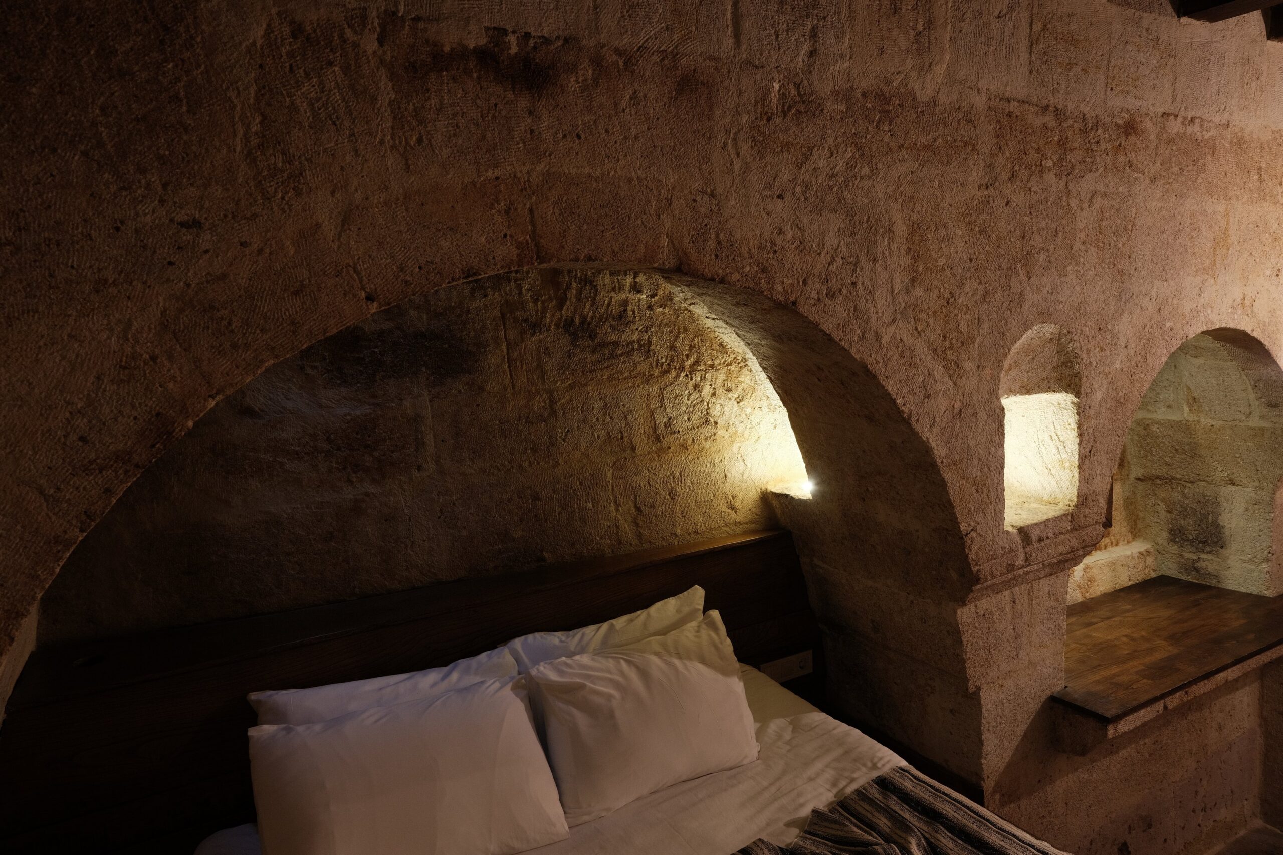 The Old Kitchen: the bed set under the arch of the bread furnace, with the lamp niche and the stove arch beyond.